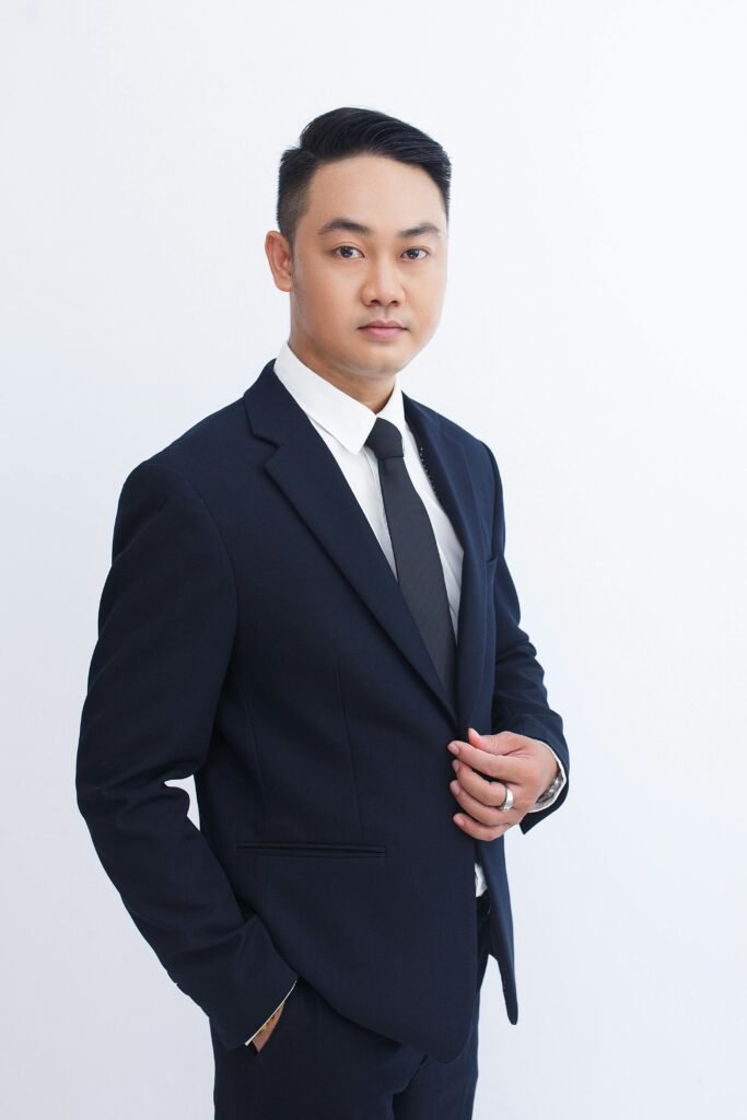 Portrait of a confident businessman in a dark suit against a white background.